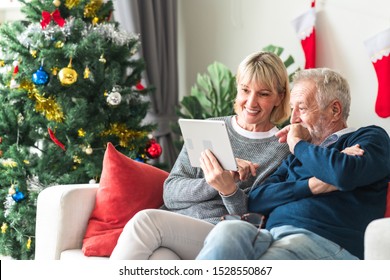 Christmas Online Shopping. Senior Caucasian Man And Woman Sitting On Couch Using Tablet In Living Room. Exciting Look.