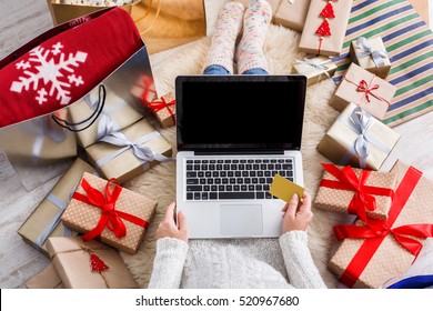 Christmas online shopping top view. Female buyer makes order on laptop with credit card, copy space on screen. Woman buy presents, prepare to xmas, among gift boxes and packages. Winter holidays sales