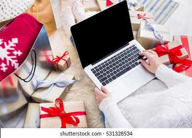 Christmas online shopping top view. Female buyer makes order on laptop computer, copy space on screen. Woman buy presents, prepare to xmas, among gift boxes and packages. Winter holidays sales