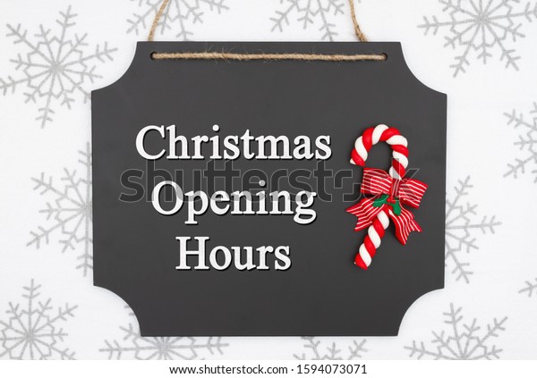 Christmas opening hours message\
on hanging chalkboard with a candy cane and white and gray\
snowflakes