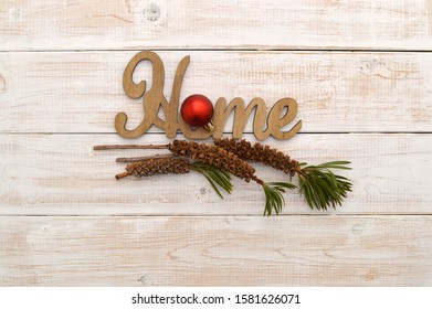 Christmas Ornament On Home Sign With Bottlebrush Plant Seed Pods On Whitewashed Wood Background