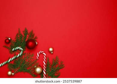 Christmas ornaments, thuja branches, and candy cane arranged on a red background for festive holiday decor - Powered by Shutterstock