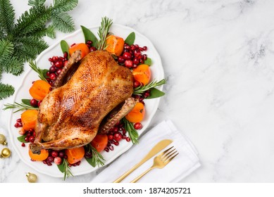 Christmas Oven Roasted Duck On A White Plate Decorated With Cranberries, Pomegranate, Persimmon, Rosemary And Sage. Marble Background. Copy Space. Chrismas Food Concept. 