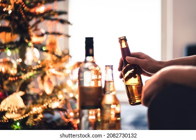 Christmas Party With Alcohol Bottles. New Year's Celebration. Beer, Wine And Vodka. Festive Xmas Tree. Alcoholism And Drinking Problem Concept. Lonely Unhappy Man With Beverage And Cocktail In Winter.