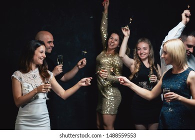 Christmas party. Celebration atmosphere. Friends dancing with champagne glasses and sparkles on New Year's Eve - Shutterstock ID 1488559553
