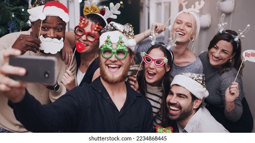 Christmas, party and friends taking a selfie on a phone together with goofy, funny and silly props. Diversity, festive and happy people taking picture on a smartphone at festive xmas event at a home. - Powered by Shutterstock