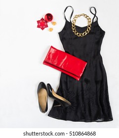 Christmas Party Outfit. Cocktail Dress Outfit, Night Out Look On White Background. Little Black Dress, Red Evening Clutch, Black Shoes, Gold Necklace. Flat Lay, Top View