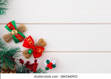 Christmas for pets. Dogs bones wrapping in red and green Christmas bows as a gift, jingle bell and pine branches on white wooden background with copy space. - Powered by Shutterstock