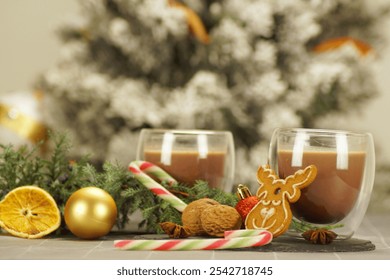 
Christmas picture - two clear glass cups with cocoa or hot chocolate. Festive decor - gingerbread cookies, candy canes, nuts, pine branch, Christmas balls, against the background of a New Year tree - Powered by Shutterstock