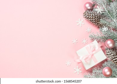 Christmas pink flat lay background with christmas present box, fir tree and decorations on pink layout. Top view with copy space.