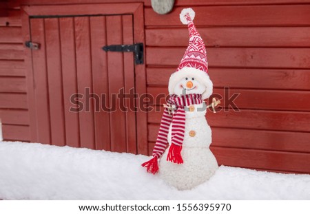 Christmas plush snowman. Stuffed snowman outdoor on snow. Stuffed animal.