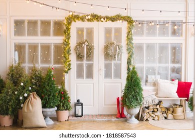 The Christmas Porch Is Decorated With Small Christmas Trees And Lanterns. Bench With Pillows Near The Front Door Of The House