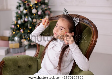 Christmas portrait of a beautiful girl with long blond hair in a playful mood depicts different emotions, beauty smiling child with long blond hair in a good mood