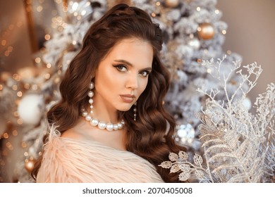 Weihnachtsporträt eines schönen Mädchenmodells mit Schminke und langer, lockiger Frisur-Stil posiert über Bokeh-Weihnachtsbaum. Romantische Frau in rosafarbenem Pelzmantel, die sich unter der Kamera posiert.