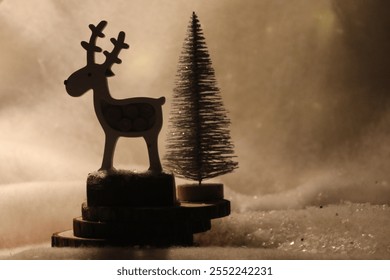 Christmas postcard with a reindeer and a tree, with snow in the background and warm light. Defocused golden background lights. Reindeer with dark silhouette - Powered by Shutterstock