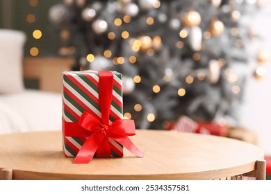 Christmas present on table against blurred Christmas tree in living room, closeup - Powered by Shutterstock