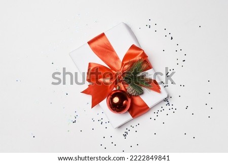 a christmas present wrapped in red ribbon and decorated with pine cones on a white surface surrounded by confe