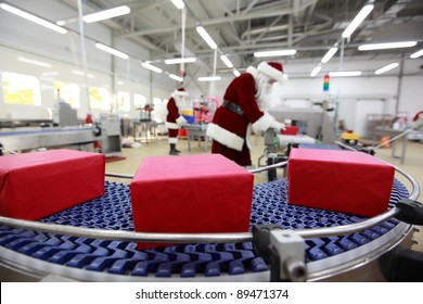 Christmas Presents Factory.three Presents  At Production Line,two Santa Clauses Workers In The Background