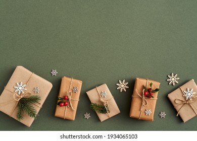 Christmas presents wrapped in ecological recycled paper with wooden decoration and wintergreen - zero-waste concept, top view