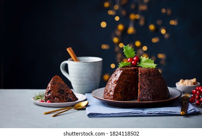 Christmas Pudding, Fruit Cake With Cup Of Tea. Traditional Festive Dessert. Dark Background With Lights Garland. Copy Space.