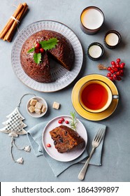 Christmas pudding, fruit cake with cup of tea. Traditional festive dessert. Grey background. Top view.