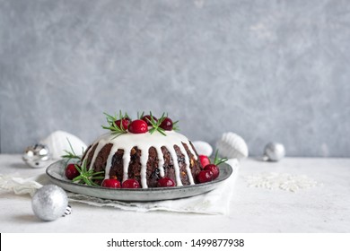 Christmas Pudding, Fruit Cake decorated with icing and cranberries on grey table, copy space. Homemade traditional Christmas festive dessert - Christmas Pudding.