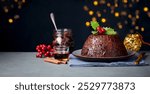 Christmas pudding, fruit cake. Traditional festive dessert. Dark background with lights garland. Copy space. Close up.