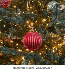 Christmas red ornament close-up Christmas tree flickering light hanging on beautifully lit. Festive bauble is surrounded by glowing string lights pine branches, creating warm cozy holiday atmosphere. - Powered by Shutterstock