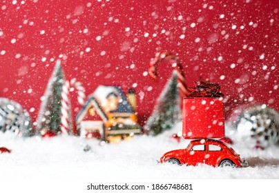 Christmas Red Retro Car With Gift Box In Red Snow Landscape On Bokeh Background. Space For Text. Concept Of Delivery Of Goods And A Greeting Card Happy New Year. Moscow, Russia-December 3, 2020