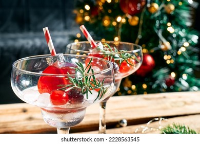 Christmas refreshment drink mimosa, punch or cranberry margarita cocktail serving in christmas ornaments and martini drinking glasses. Delicious icy drink idea for christmas and winter holiday party. - Shutterstock ID 2228563545