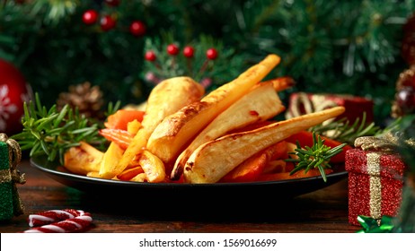 Christmas Roasted Parsnips and Carrots with decoration, gifts, green tree branch on wooden rustic table