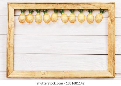 Christmas rustic background with string lights as pineapples golden colored on white in wooden frame. Festive decoration, New Year fairy garland. Flat lay. Top view, copy space.