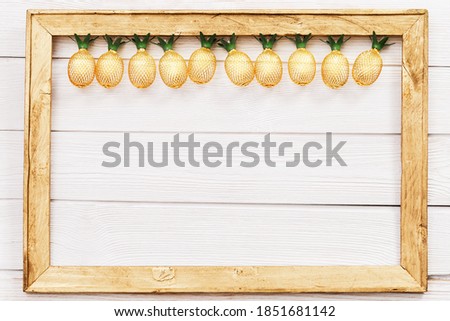 Christmas rustic background with string lights as pineapples golden colored on white in wooden frame. Festive decoration, New Year fairy garland. Flat lay. Top view, copy space.