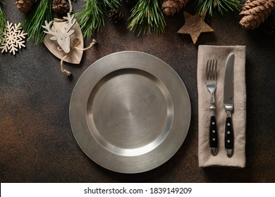 Christmas Rustic Home Table Setting With Empty Plate And Xmas Wooden Decor On Brown Table. Top View, Flat Lay.