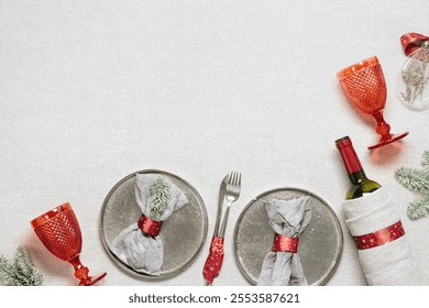 Christmas rustic table setting, red wine glass, plate, knife, fork, wine bottle, decorated green fir tree on sacking tablecloth. New Year dinner or party idea with xmas decor, serving festive table - Powered by Shutterstock