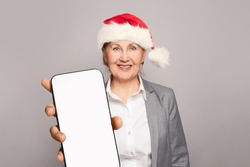 Christmas Santa Woman Showing Smartphone Display On Grey Background