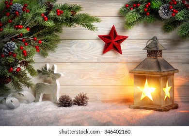 Christmas scene background with a lantern, fir branches, red star, reindeer and snow in front of a bright wooden board with candle light - Powered by Shutterstock