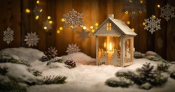 Christmas Scene With Lantern And Hanging Ornaments, Wood Background And Snow, The Burning Candle And The Brown Planks Create A Cozy Warm Mood