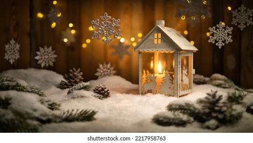 Christmas scene with lantern and hanging ornaments, wood background and snow, the burning candle and the brown planks create a cozy warm mood - Powered by Shutterstock