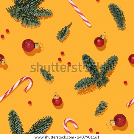 Christmas seamless pattern with fir branches, baubles balls and candy cane cane on yellow background