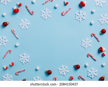 Christmas season border frame with candy canes, snow and holly berries on pastel blue background. Creative New Year or Merry Xmas holiday composition. Winter greeting card with copy space. Flay lay. - Powered by Shutterstock