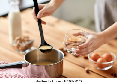 Christmas And Seasonal Drinks Concept - Close Up Of Hands With Ladle Pouring Eggnog From Pot To Glass At Home