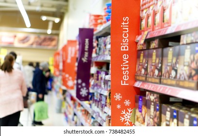 Christmas Shoppers In A Supermarket Aisle With Focus On A Festive Biscuits Sign.