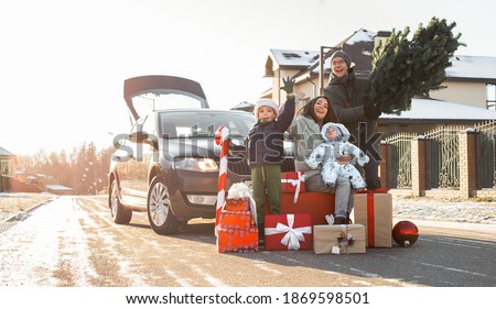 Christmas shopping and family preparation for winter holidays. Happy parents and cheerful children with many gifts and Xmas fir tree outside near car in town or country. Family of four
