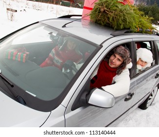 Christmas Shopping - The Family Is Riding A Car With Christmas Tree And Gifts On The Roof Of The Car