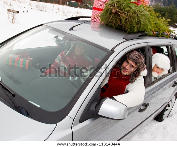 Christmas shopping - the family is\
riding a car with christmas tree and gifts on the roof of the\
car