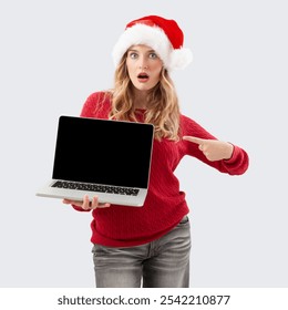 Christmas shopping online, amazed woman in santa hat showing pointing laptop computer blank screen, advertising banner for top offers in sales of Christmas shopping web store or booking holiday travel - Powered by Shutterstock