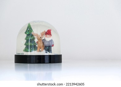 Christmas snow globe featuring Santa Claus, his reindeer and a Christmas tree, on white snowy background, festive ornament decoration, copy space on the right - Powered by Shutterstock