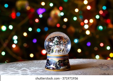 Christmas Snow Globe in front of Christmas tree lights closeup, blurred background - Powered by Shutterstock