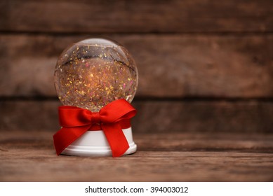 Christmas snow globe with red ribbon bow on wooden background - Powered by Shutterstock